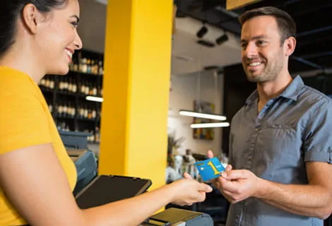 Smiling man handing a Golden 1 credit card to smiling woman to make a purchase