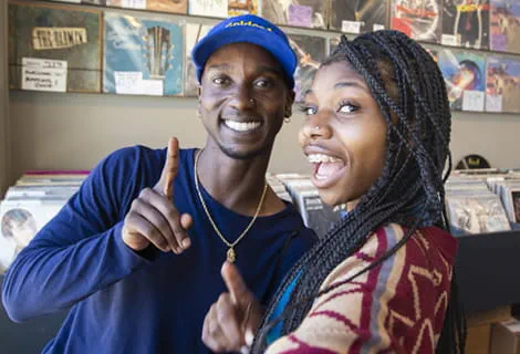 Smiling man and woman posing for selfie in a record store