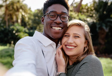 Young smiling man and woman standing close to one another taking a selfie