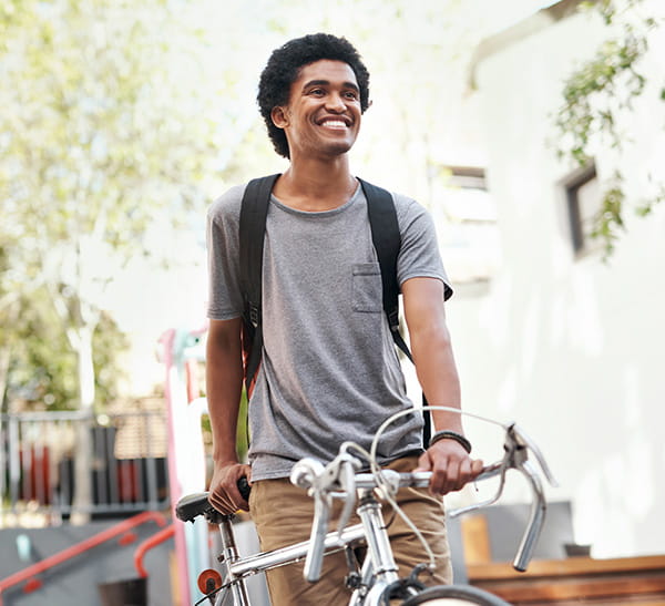 Young male student with backpack on bicycle