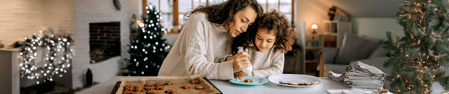 Mom and daughter icing cookies in a Christmas scene