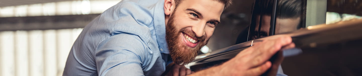 Smiling man closely admiring the finish on a car