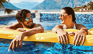 A man and woman laughing in the pool, hanging onto a floaty.