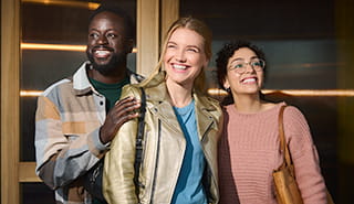 2 women and a man smiling while looking out and up