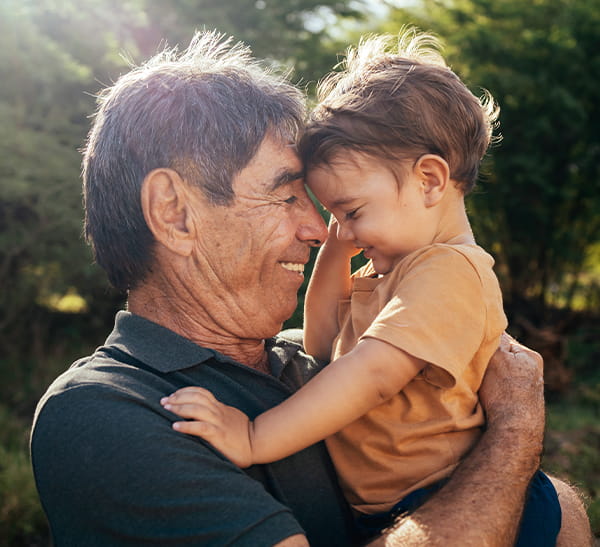 Grandfather holding up his grandson with their foreheads pressed against each other.