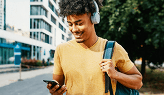 Male student with backpack over shoulder looking at cell phone