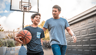 Son and dad playing basketball in driveway