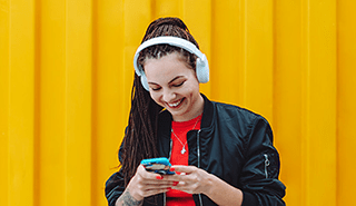 Woman looking down at her phone with headphones on