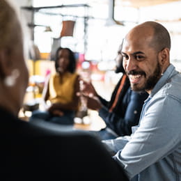 Group of adults meeting around a table, smiling man in foreground