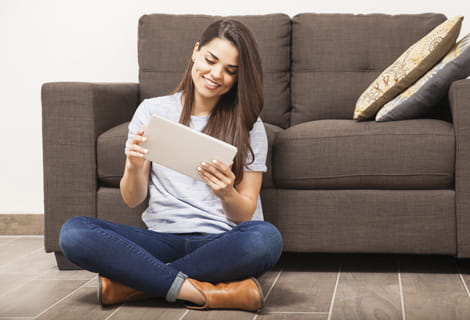 woman looks at tablet on living room floor